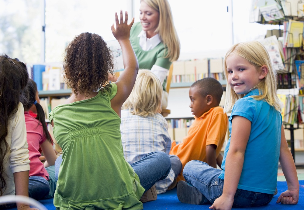 children sitting on the floor with one lady sitting in front of them 
